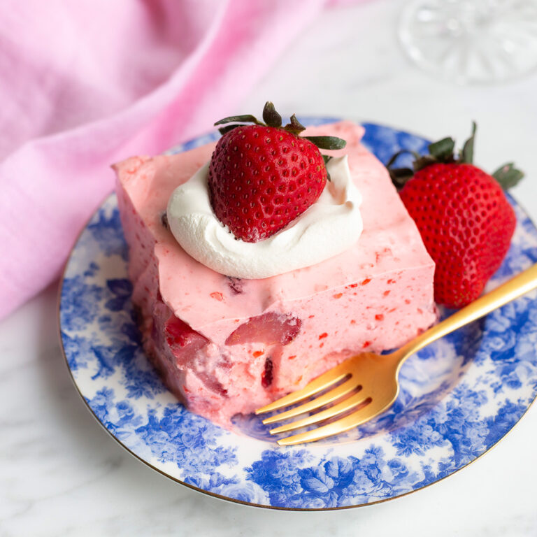strawberry jello salad topped with cool whip and fresh strawberries