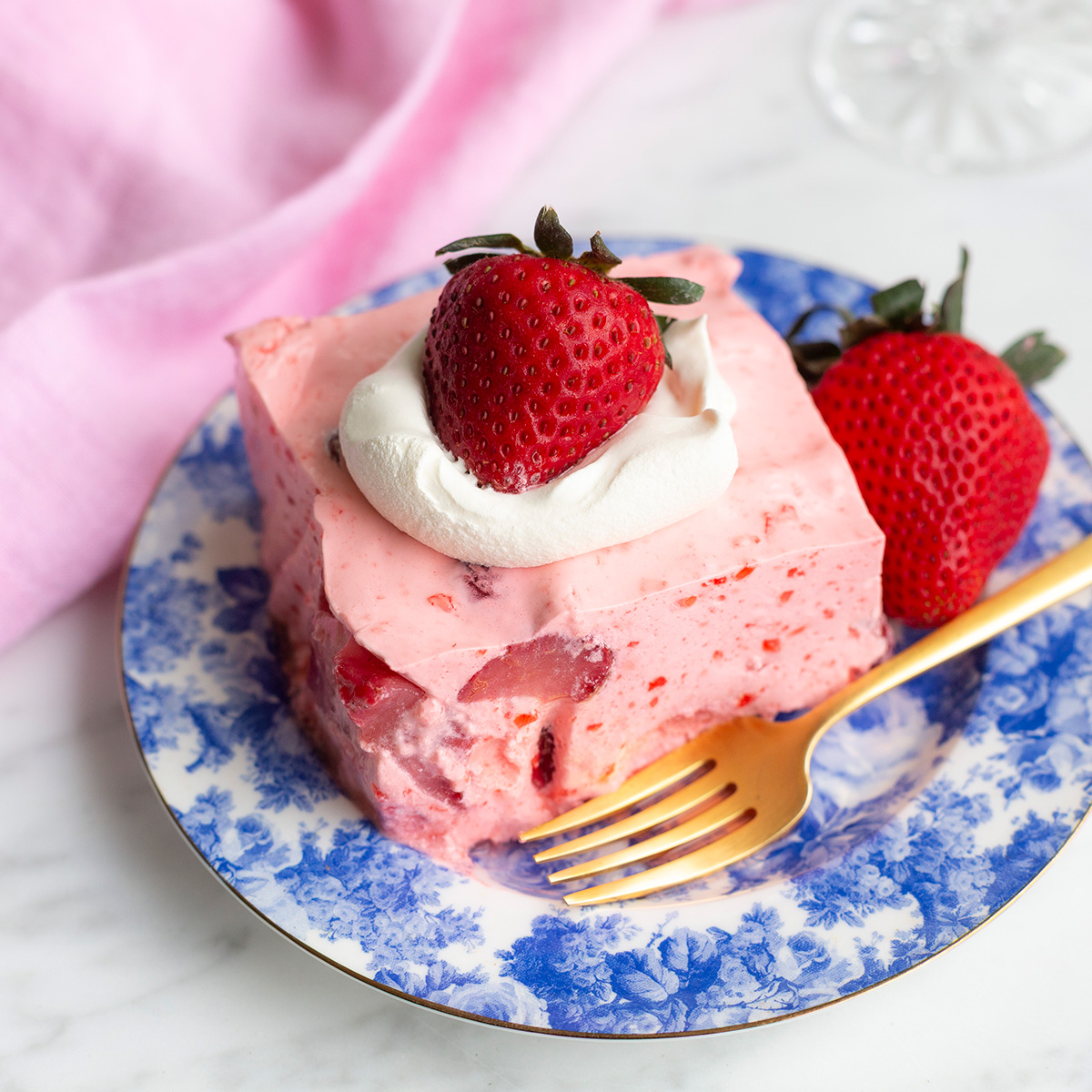 strawberry jello salad topped with cool whip and fresh strawberries